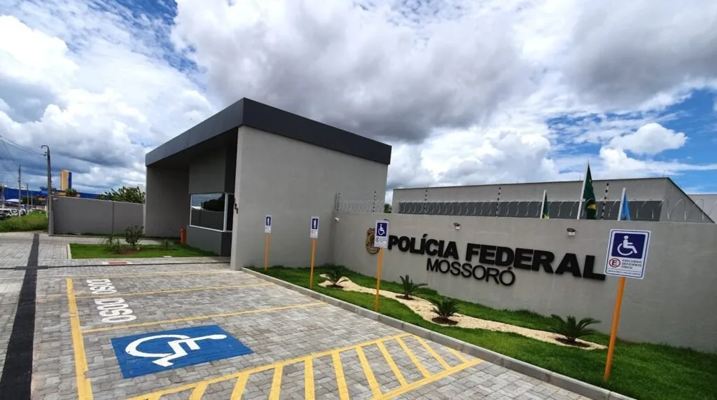 Fachada de prédio com letreiro 'Polícia Federal Mossoró' e vagas de estacionamento em frente