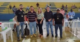 Grupo de cinco pessoas posando para foto em salão de evento fechado