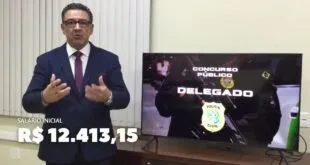 Homem de terno fala ao lado de tela com anúncio de concurso público para delegado