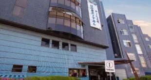 Fachada de prédio hospitalar com revestimento azul e branco vista da calçada