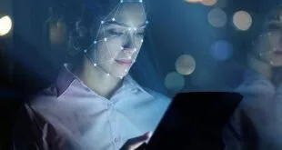 Mulher diante de tela iluminada com malha de pontos de reconhecimento facial sobre o rosto