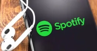 Logotipo verde do Spotify em tela escura ao lado de estrutura desfocada