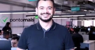 Homem jovem sorridente de camisa polo azul em ambiente de escritório