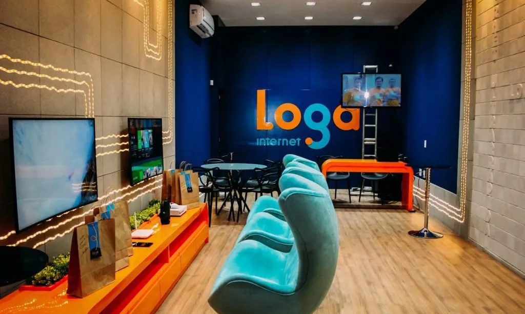 Recepção com sofá azul e parede com o logotipo 'Loga' em ambiente de escritório colorido