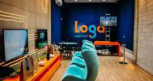 Recepção com sofá azul e parede com o logotipo 'Loga' em ambiente de escritório colorido