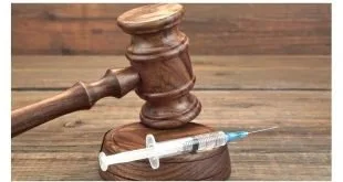 Martelo de juiz de madeira ao lado de uma seringa sobre mesa, imagem ilustrativa