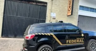 Viatura preta da Polícia Federal estacionada em frente a um estabelecimento fechado