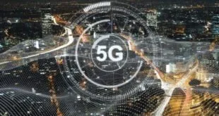 Vista noturna de cidade iluminada com o símbolo '5G' em destaque sobre a paisagem