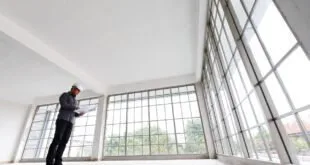 Homem observando grande janela de esquadria de alumínio em ambiente vazio em obra