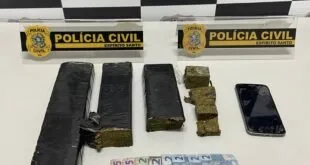 Tabletes de maconha, celular e cédulas sobre mesa diante de painel da Polícia Civil do Espírito Santo