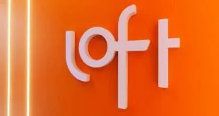 Letreiro branco com a marca 'loft' em relevo sobre parede laranja