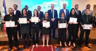 Grupo de pessoas em traje formal segurando certificados durante uma cerimônia