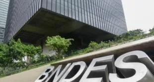 Fachada de prédio envidraçado com o letreiro 'BNDES' entre plantas