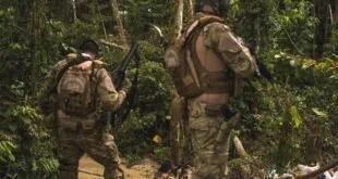 Agentes fardados com fuzis caminhando em meio à mata fechada durante operação