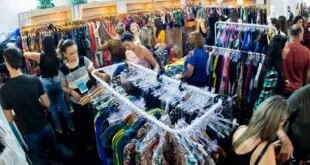 Público circulando entre araras de roupas em feira de confecção