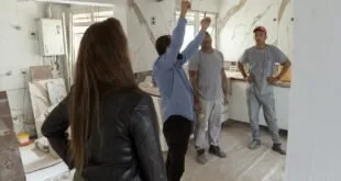 Mulher observa trabalhadores retirando revestimento de parede em cômodo em obra