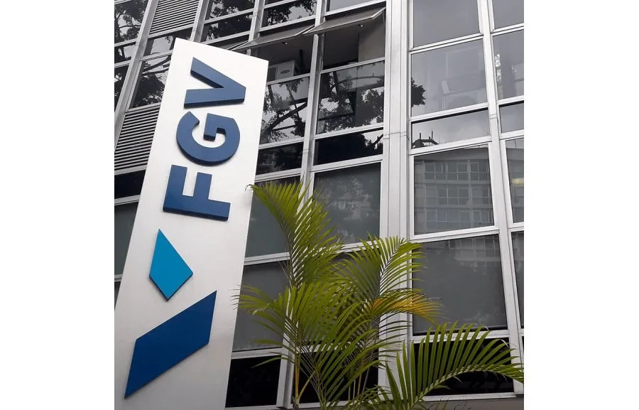 Totem com o logotipo FGV diante de prédio de vidro cercado por plantas