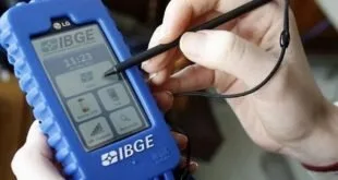 Mão segurando coletor de dados azul com a marca IBGE e caneta digital