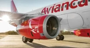 Avião da Avianca parado na pista com o motor em primeiro plano ao amanhecer