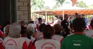 Pessoas de camiseta do Corpo de Bombeiros reunidas em evento sob tenda ao ar livre