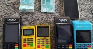 Maquininhas de cartão, celular e maços de cédulas apreendidos sobre o chão