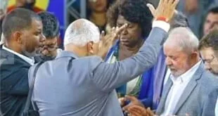 Homem de terno impõe as mãos sobre fiel durante culto com braços erguidos ao fundo