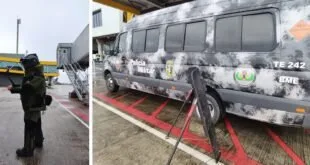 Policial com traje antibomba em pátio de aeroporto e van do esquadrão antibombas