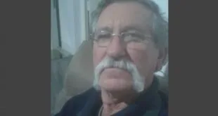 Retrato de homem idoso de óculos e bigode branco em ambiente doméstico