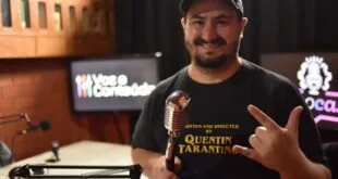 Homem de boné sorri segurando um microfone retrô em estúdio de podcast
