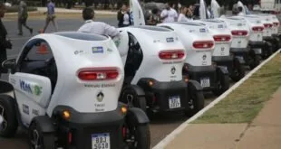 Fila de veículos elétricos compactos brancos estacionados em área gramada