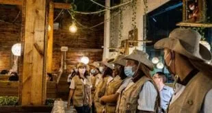 Funcionários uniformizados de chapéu reunidos no salão rústico de um restaurante