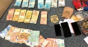 Maços de cédulas, celulares e distintivo da Polícia Federal sobre uma mesa