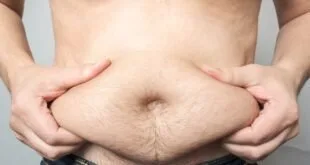 Close de barriga com dobra de gordura segurada pelas mãos da própria pessoa