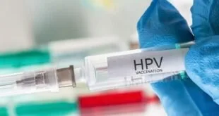Mão com luva azul segura tubo de coleta com a etiqueta 'HPV' em laboratório