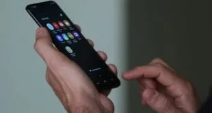 Mãos segurando celular com tela de chamada telefônica em ambiente escuro