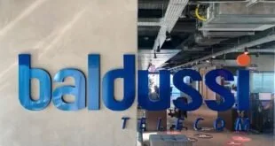 Letreiro azul da Baldussi Telecom em parede de escritório