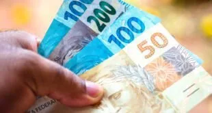 Mão segurando cédulas de real de 50, 100 e 200 reais