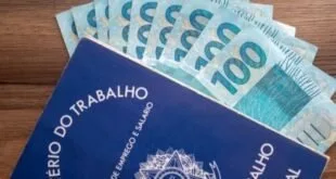 Cédulas de cem reais sobre carteira de trabalho azul