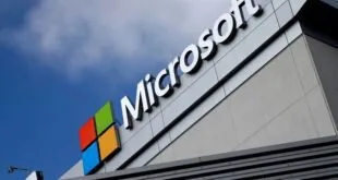 Letreiro da Microsoft com o logotipo colorido no alto de prédio sob céu azul