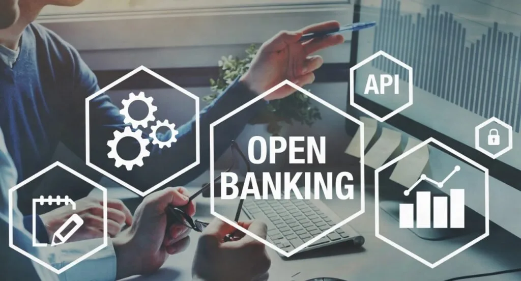 Arte com ícones de engrenagens e o texto 'Open Banking' sobre mãos usando notebook