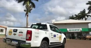 Caminhonete branca adesivada estacionada em frente a prédio com palmeiras