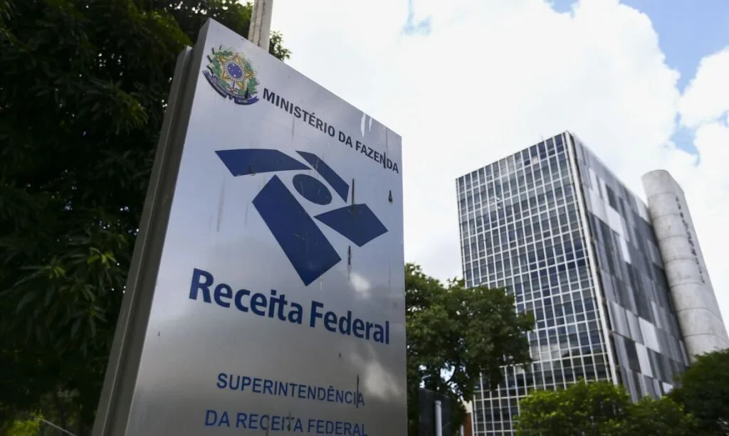 Placa com o logotipo da Receita Federal em frente a prédio público