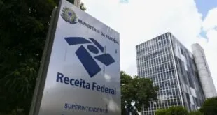 Placa com o logotipo da Receita Federal em frente a prédio público