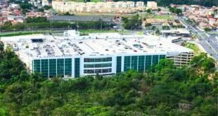 Vista aérea de shopping center com estacionamento no telhado cercado por mata