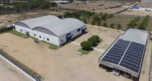 Vista aérea de galpão industrial com placas de energia solar instaladas ao lado