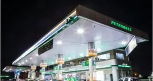 Posto de combustíveis iluminado à noite com bombas e loja de conveniência