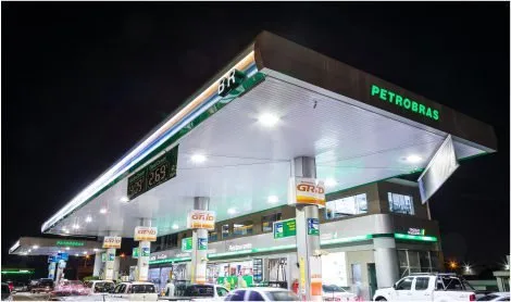Posto de combustíveis iluminado à noite com bombas e loja de conveniência