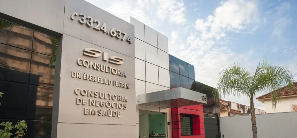 Fachada de prédio comercial com letreiro de consultoria de negócios em saúde e palmeira ao lado