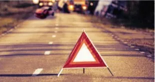 Triângulo de sinalização vermelho sobre a pista com carros desfocados ao fundo