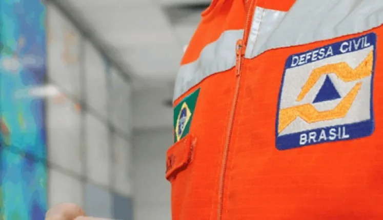 Detalhe de uniforme laranja com bandeira do Brasil e brasão costurados no braço